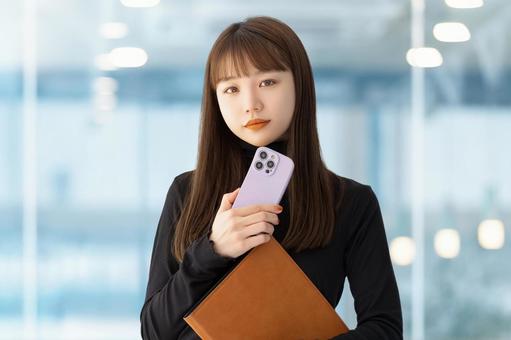 スマホとバインダーを持つ女性 女性,ビジネス,スマホの写真素材