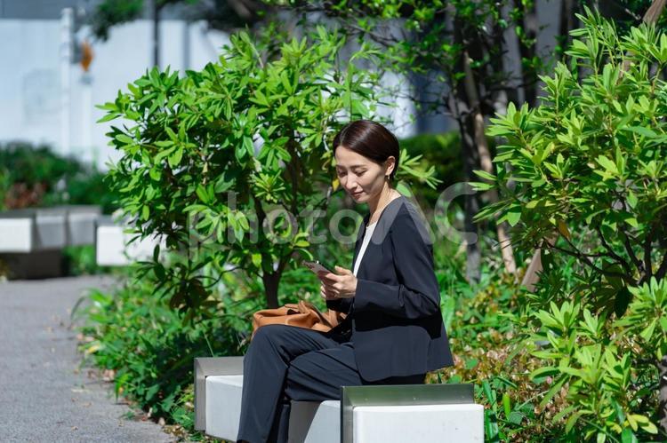 携帯を見るスーツを着た女性 スーツ,人物,会社員の写真素材