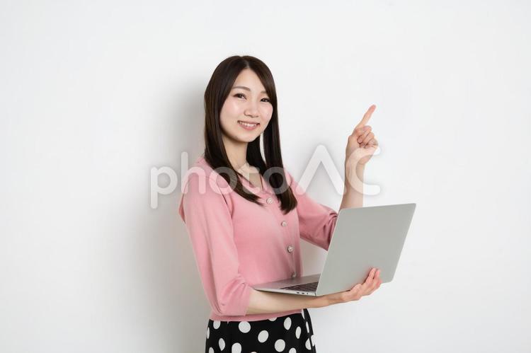 パソコンを持って指差ししている若い女性 女性,日本人,女の写真素材