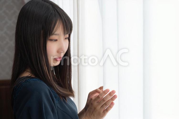 窓際でカーテンに触れている20代の女性 女性,人物,日本人の写真素材