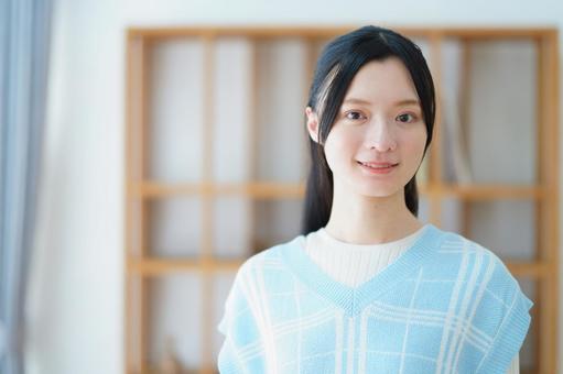 カメラ目線で微笑む青いベストの女性の写真