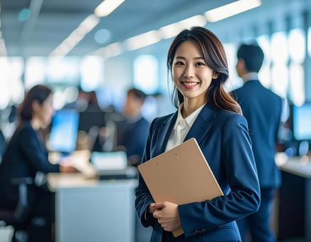 オフィスでPCを持って微笑む女性社員 オフィスでPCを持って微笑む女性社員の写真