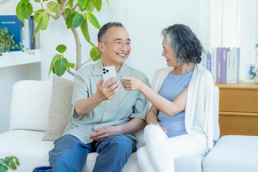 リビングでスマホを見るシニア夫婦 リビングでスマホを見るシニア夫婦 スマホ,シニア,笑顔の写真素材