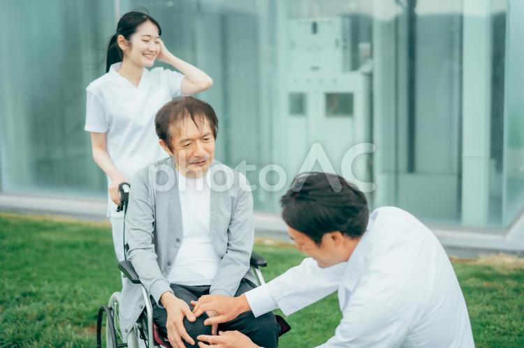 車椅子に乗った患者と医療スタッフ（3人） 車椅子,患者,病院の写真素材