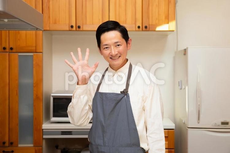 キッチンで指を５本立てている笑顔の若い日本人男性 キッチン,台所,料理の写真素材