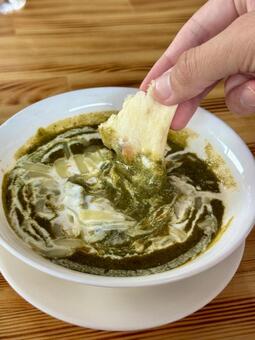 グリーンカレーにナンをつける グリーンカレー,ほうれん草のカレー,パンの写真素材