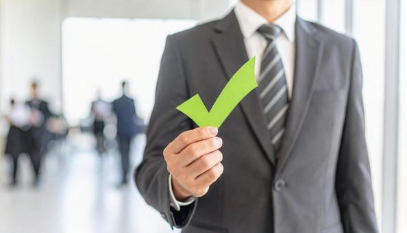 チェックマークを片手に持つビジネスマンの写真