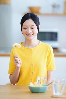 フォークに刺したリンゴを見つめる女性 女性,リンゴ,フォークの写真素材