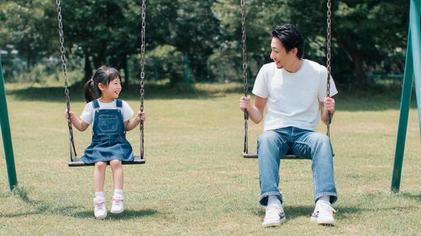 公園のブランコに乗る親子 公園のブランコに乗る親子の写真