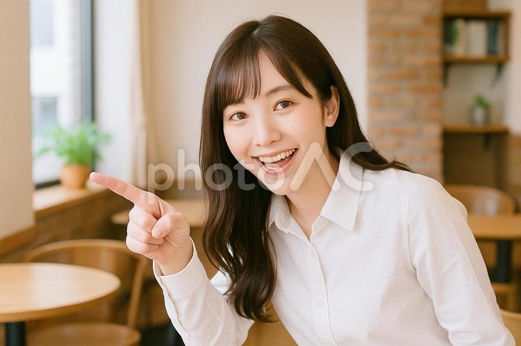 カフェで前傾指差し女性 女性,笑顔,白シャツの写真素材