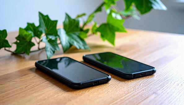 連絡交換のイメージ 机の上の携帯電話二台 連絡交換のイメージ 机の上の携帯電話二台の写真