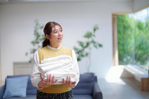 畳んだタオルを持ち振り向く女性 女性,洗濯物,タオルの写真素材