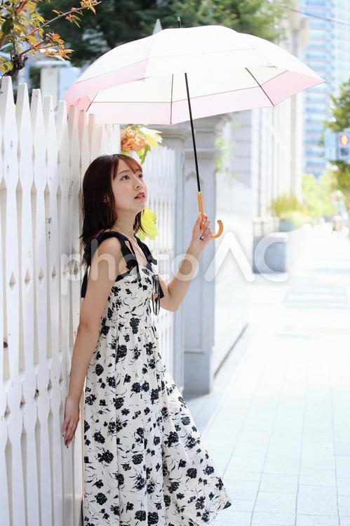 白い塀にもたれて景色を眺める女性 女性,美人,日傘の写真素材
