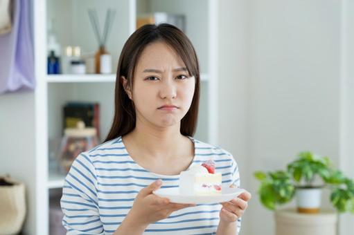 ケーキで悩む若い女性 悩む,ダイエット,ケーキの写真素材
