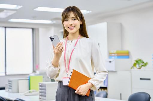 オフイスでスマホを使う笑顔の女性会社員 スマートフォン,ビジネスウーマン,笑顔の写真素材