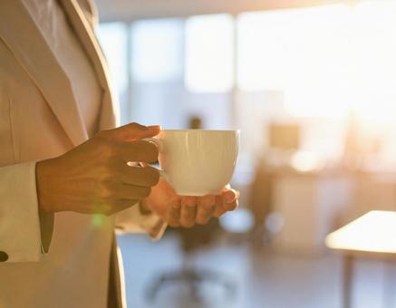 コーヒーを持つビジネスウーマンの手元 コーヒーを持つビジネスウーマンの手元の写真