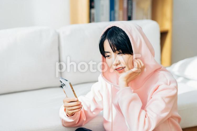  部屋でスマホを操作する若い女性 女性,スマホ,スマートフォンの写真素材