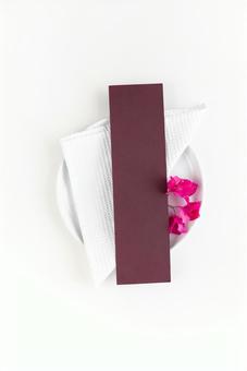 白いお皿に添えられたピンクの花と茶色いカード 白いお皿に添えられたピンクの花と茶色いカード モックアップ,物撮り,テーブルコーディネートの写真素材