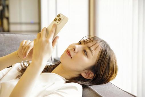 A young woman relaxing and enjoying her smartphone, JPG