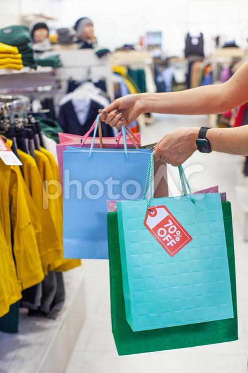 洋服売り場で紙袋を持っている女性の手元 セール,ショップ,女性の写真素材