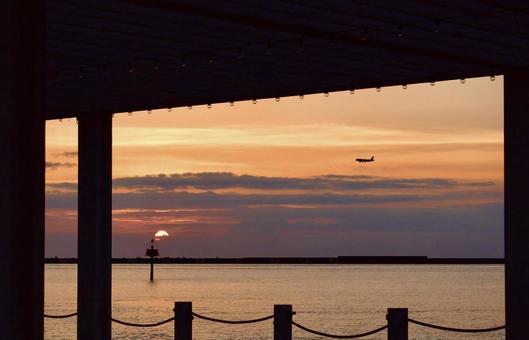 窓から見える夕日と空を飛ぶ飛行機 窓から見える夕日と空を飛ぶ飛行機 夕暮れ,夕日,夕焼けの写真素材