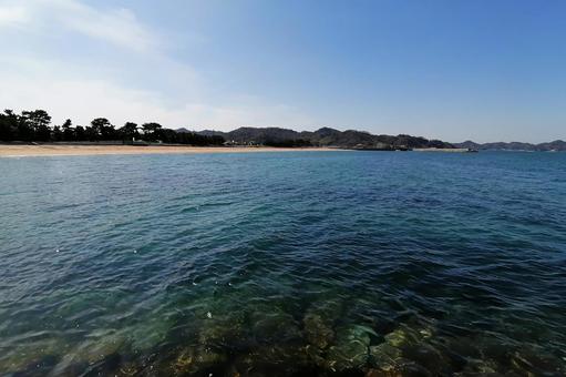 青い空とエメラルドグリーンの海と海岸線の写真
