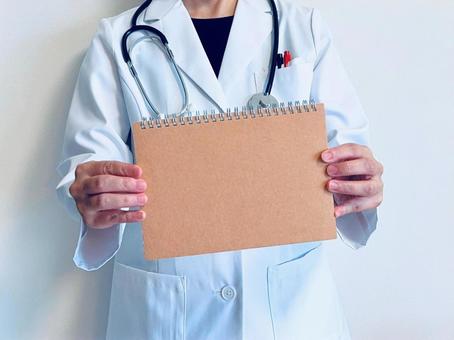 茶色いノートを掲げる女性医師 女医,ドクター,医師の写真素材