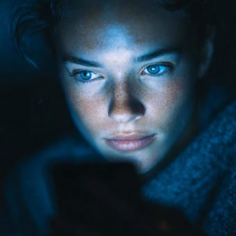 夜の静寂の中、スマホの光に照らされる目の写真