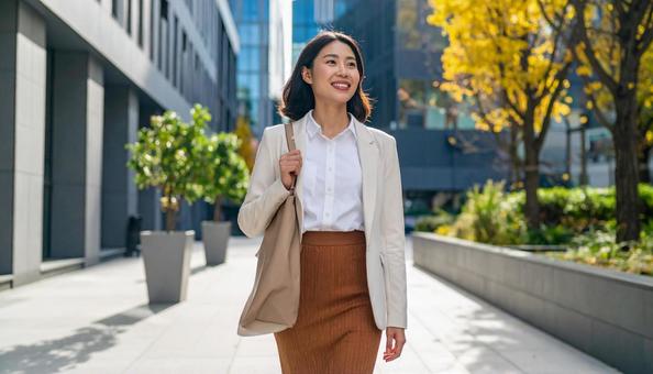 秋のオフィス街を歩く笑顔の女性 秋のオフィス街を歩く笑顔の女性の写真