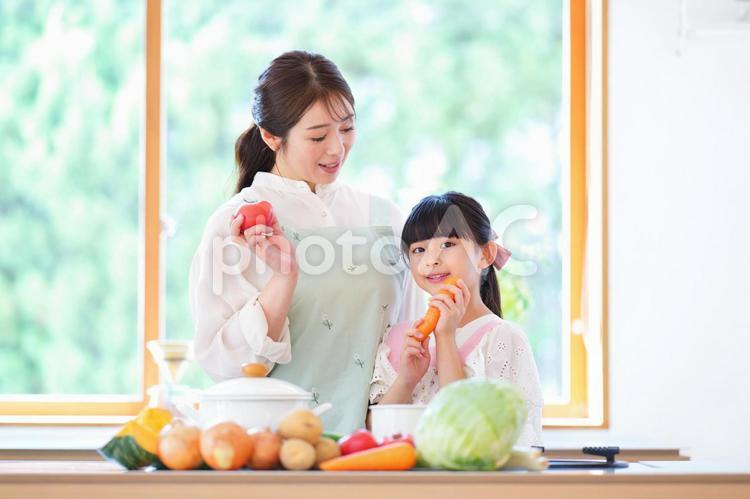 ニンジンを持つ娘を見る母 母,娘,寄り添うの写真素材