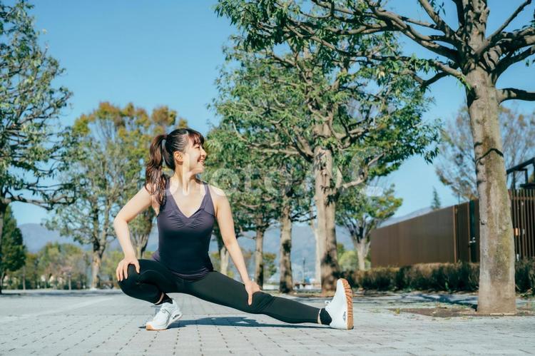 公園で準備運動する女性（屈伸） 準備運動,屈伸,散歩の写真素材