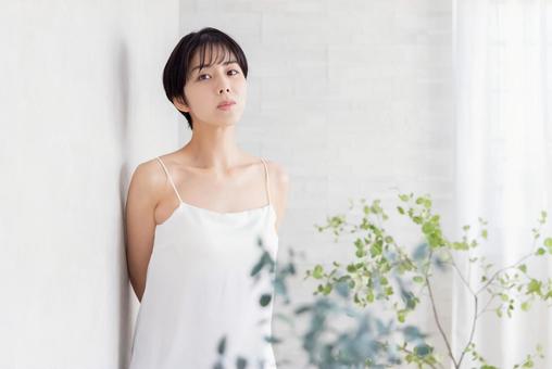 壁に寄りかかるキャミソールの女性 壁に寄りかかるキャミソールの女性の写真