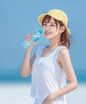 水分補給をする帽子を被った女性 水分補給をする帽子を被った女性の写真