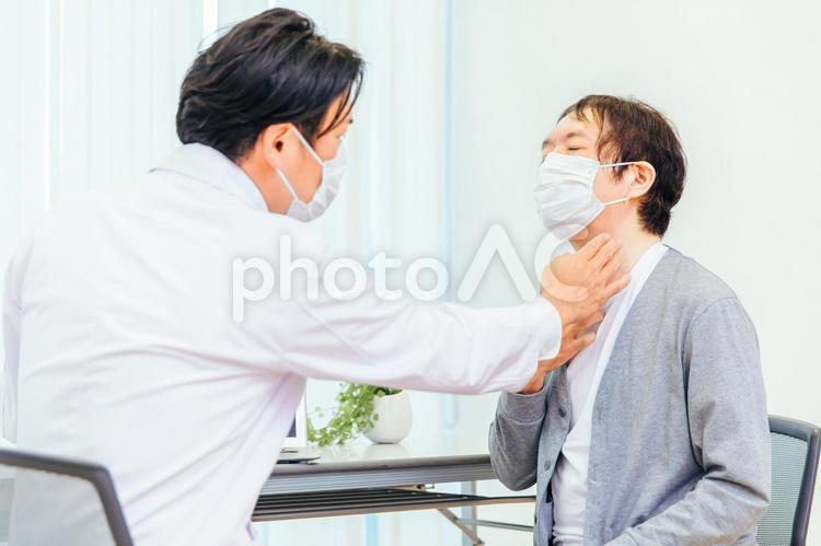パソコンで診察するマスク姿の男性医師（のど） 喉,のど,病気の写真素材
