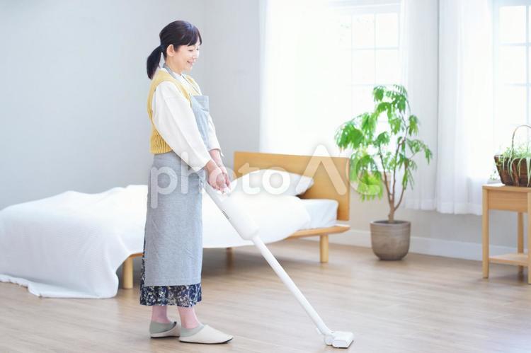明るい寝室で掃除機をかける女性 家政婦,主婦,シニアの写真素材