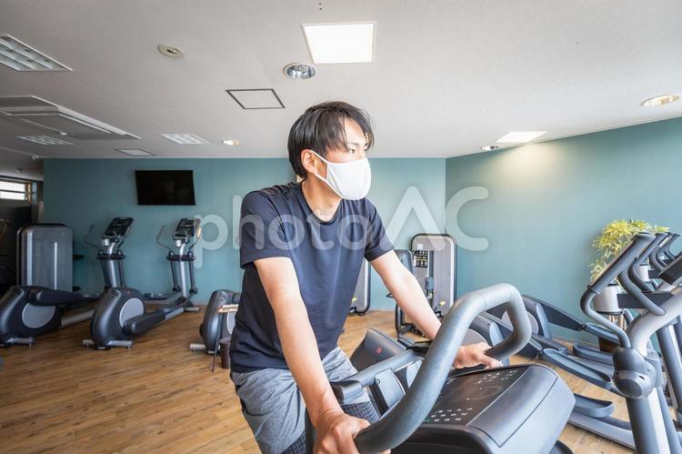エアロバイクで運動する男性（マスク） エアロバイク,マスク,有酸素運動の写真素材