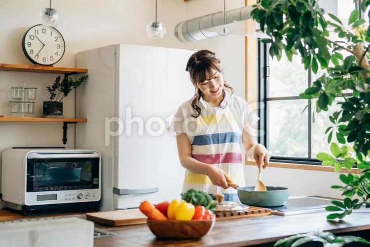 キッチンでフライパンを使う女性（笑顔） 料理,新生活,調理の写真素材