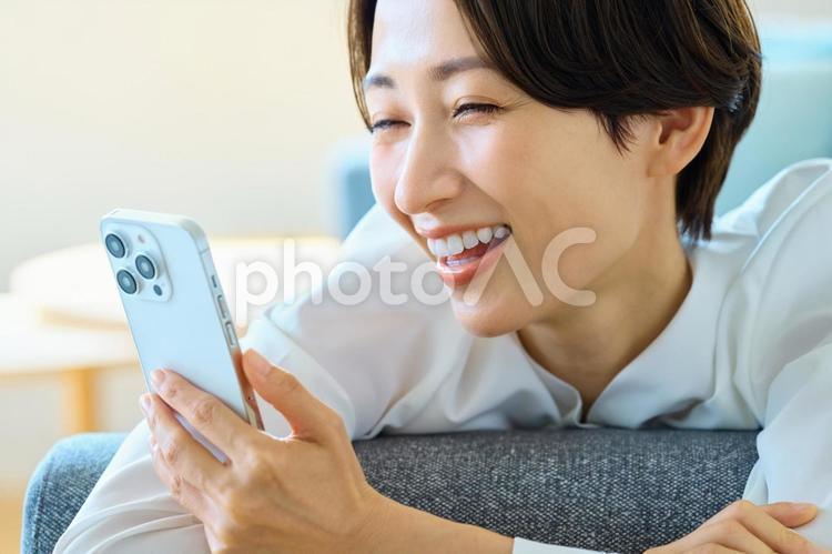 ソファでスマホを見る女性 主婦,スマホ,スマートフォンの写真素材