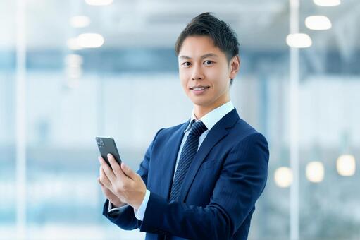 スマホを持つ笑顔の男性ビジネスマン 男性,スマホ,ビジネスの写真素材