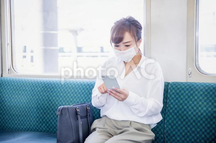 電車の中でマスクをする女性 電車,スマホ,マスクの写真素材