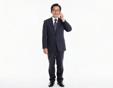 携帯電話で通話する年配のビジネスマン全身 携帯電話で通話する年配のビジネスマン全身の写真