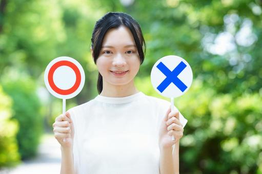 白いノースリーブの女性がマルバツカードをもって笑顔を見せる 女性,クイズプレート,持つの写真素材