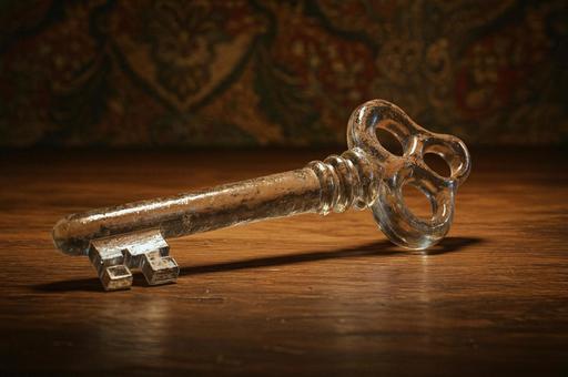 経年感のあるガラスの鍵と木のテーブルの写真