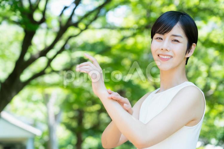 緑の中でスキンケアをする若い女性 スキンケア,ビューティー,女性の写真素材
