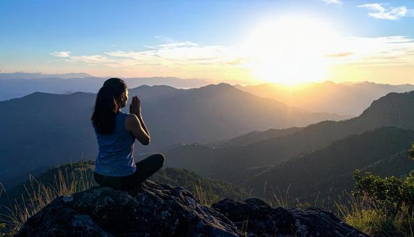 夕焼けに手を合わせて祈る女性 夕焼けに手を合わせて祈る女性の写真