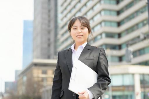 屋外でバインダーを持つスーツの女性 屋外でバインダーを持つスーツの女性の写真