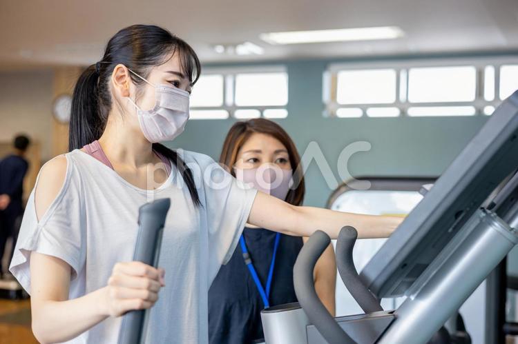 スポーツジムで指導を受ける女性（マスク） スポーツジム,有酸素運動,トレーニングの写真素材