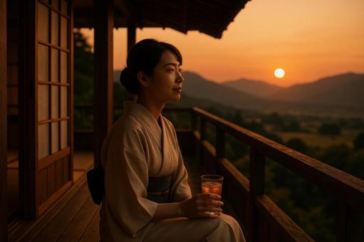 テラスで夕日を眺める女性の写真