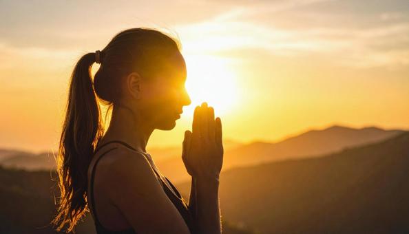 夕焼けに手を合わせて祈る女性 夕焼けに手を合わせて祈る女性の写真