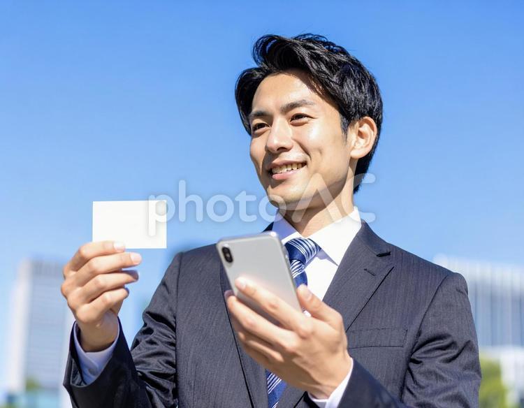 スマホ 名刺 男性 ビジネスマン 屋外 30代,スマホ,名刺の写真素材